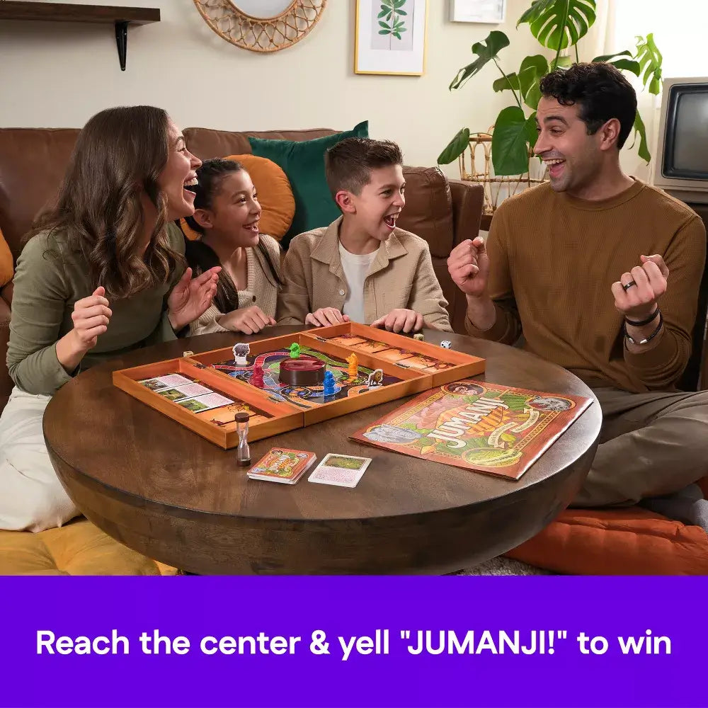 Family of four smiling and cheering around wooden table while playing Jumanji board game, with jungle-themed cards, hourglass, and pieces on board.