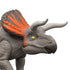 Jurassic World Zuniceratops close-up featuring gray textured plastic skin, curved white horns, orange-accented frill, and bright yellow eye, emphasizing detailed sculpting and realistic toy design on a white background.