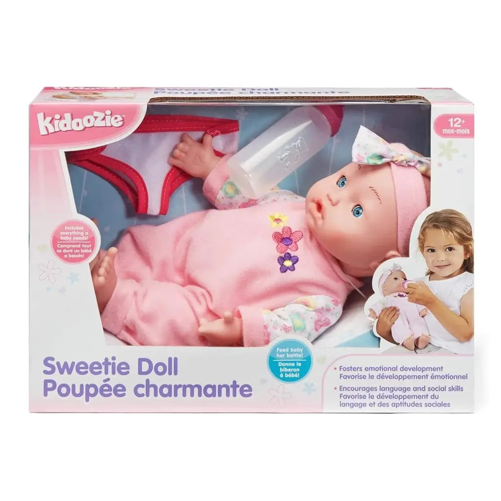 Kidoozie Sweetie Doll in retail packaging shows 12-inch baby doll in pink outfit with floral details, bottle, diaper, and product features in English and French.