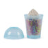 Clear plastic smoothie cup filled with layered yellow, white, pink, and mixed Kinetic Sand topped with molded swirl, showing smooth texture and colorful blending effect on a white background.