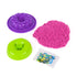 Kinetic sand playset in bright pink granular texture with purple and green plastic molds, donut shapes and sprinkle packet, designed for creative pretend dessert play on a clean white background.