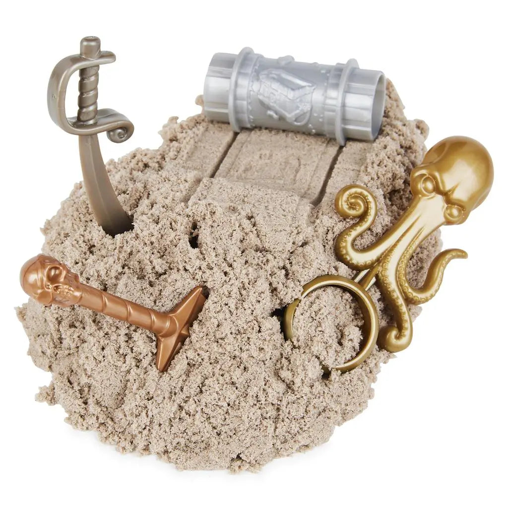 Brown Kinetic Sand mound with pirate-themed tools including a sword, shovel, octopus ring, and barrel, highlighting soft moldable texture and interactive treasure hunt play on a white background.