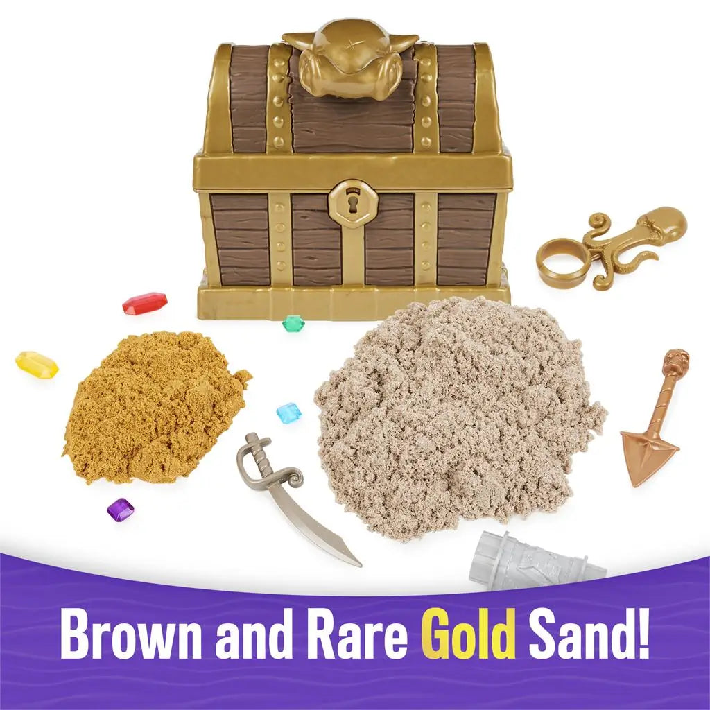 Brown and gold Kinetic Sand treasure hunt set showing toy chest, brown and gold sand piles, plastic sword, shovel, gems, octopus ring, and accessories arranged for discovery play on white.