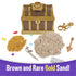 Brown and gold Kinetic Sand treasure hunt set showing toy chest, brown and gold sand piles, plastic sword, shovel, gems, octopus ring, and accessories arranged for discovery play on white.