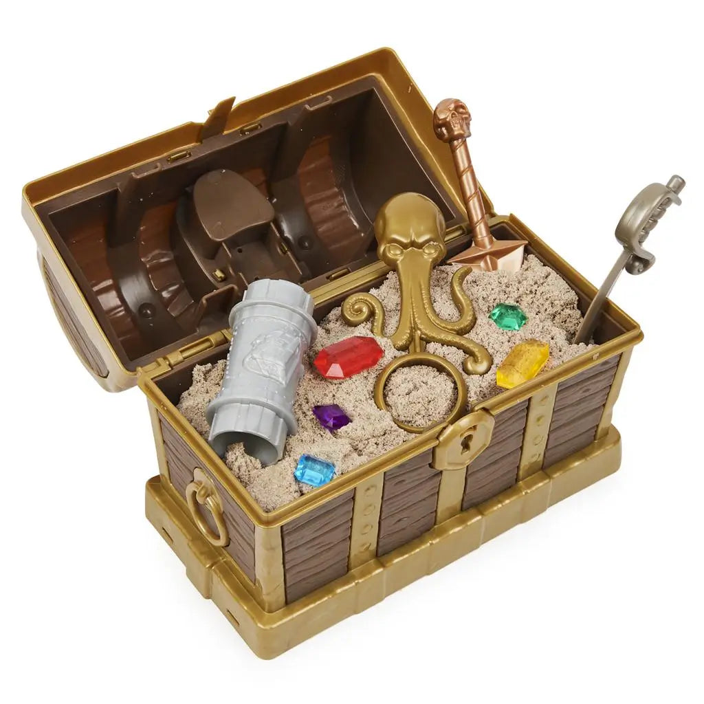 Brown and gold Kinetic Sand treasure hunt playset chest with molded wood texture, metallic trim, and pirate theme, opened to reveal kinetic sand, gems, tools, and hidden compartments on white.