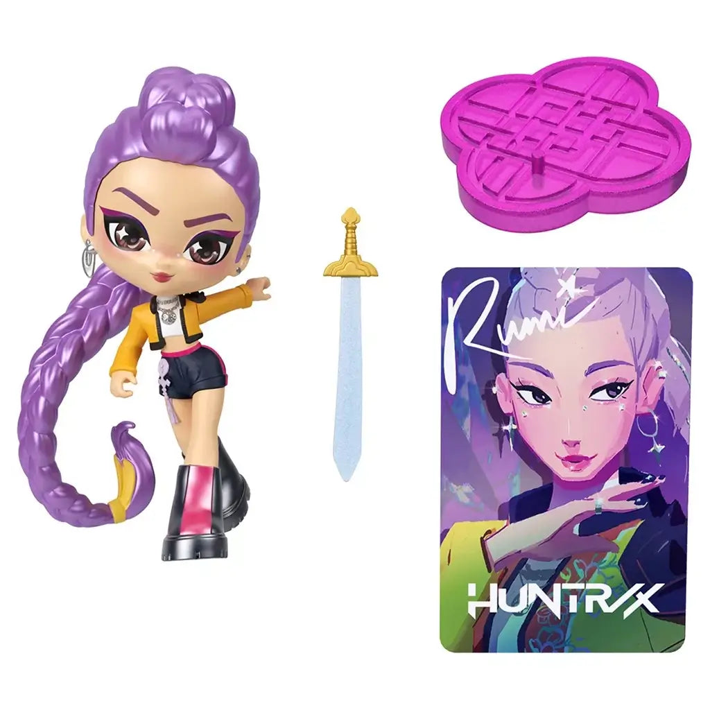 KPop Demon Hunters Rumi collectible figure in purple, yellow and black plastic is shown with a blue sword, purple display base and illustrated Huntrix character card on white.