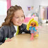 Smiling child holding the LOL Surprise Tweens Hana Groove doll with bright yellow hair, pink boots, and blue jacket in a cozy bedroom decorated with soft pink tones and playful wall art.