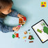 LEGO Animal Crossing Goldie's Cozy House playset shows a child assembling the tan cottage with digital building instructions on a tablet across a light blue tabletop with detailed LEGO elements and realistic display presentation.