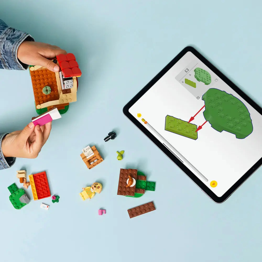 LEGO Animal Crossing Goldie's Cozy House playset shows hands building the cottage with Goldie, accessories and a tablet displaying interactive instructions on a light blue table with detailed LEGO elements and realistic display presentation.