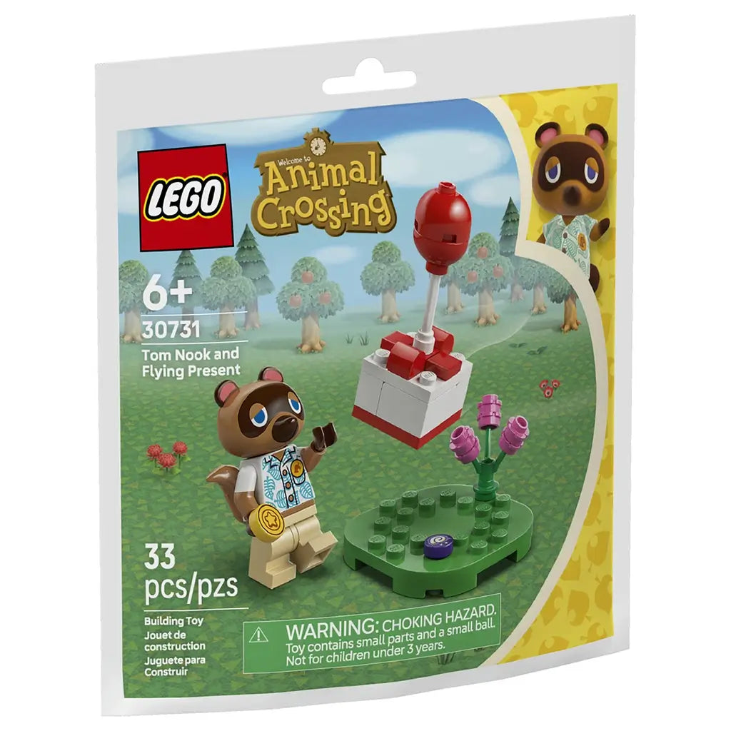 LEGO Animal Crossing Tom Nook set features a colorful plastic minifigure with brown and tan tones, green base plate, pink flowers, and a red balloon gift build, themed as a playful island scene, shown on branded packaging with illustrated forest background.