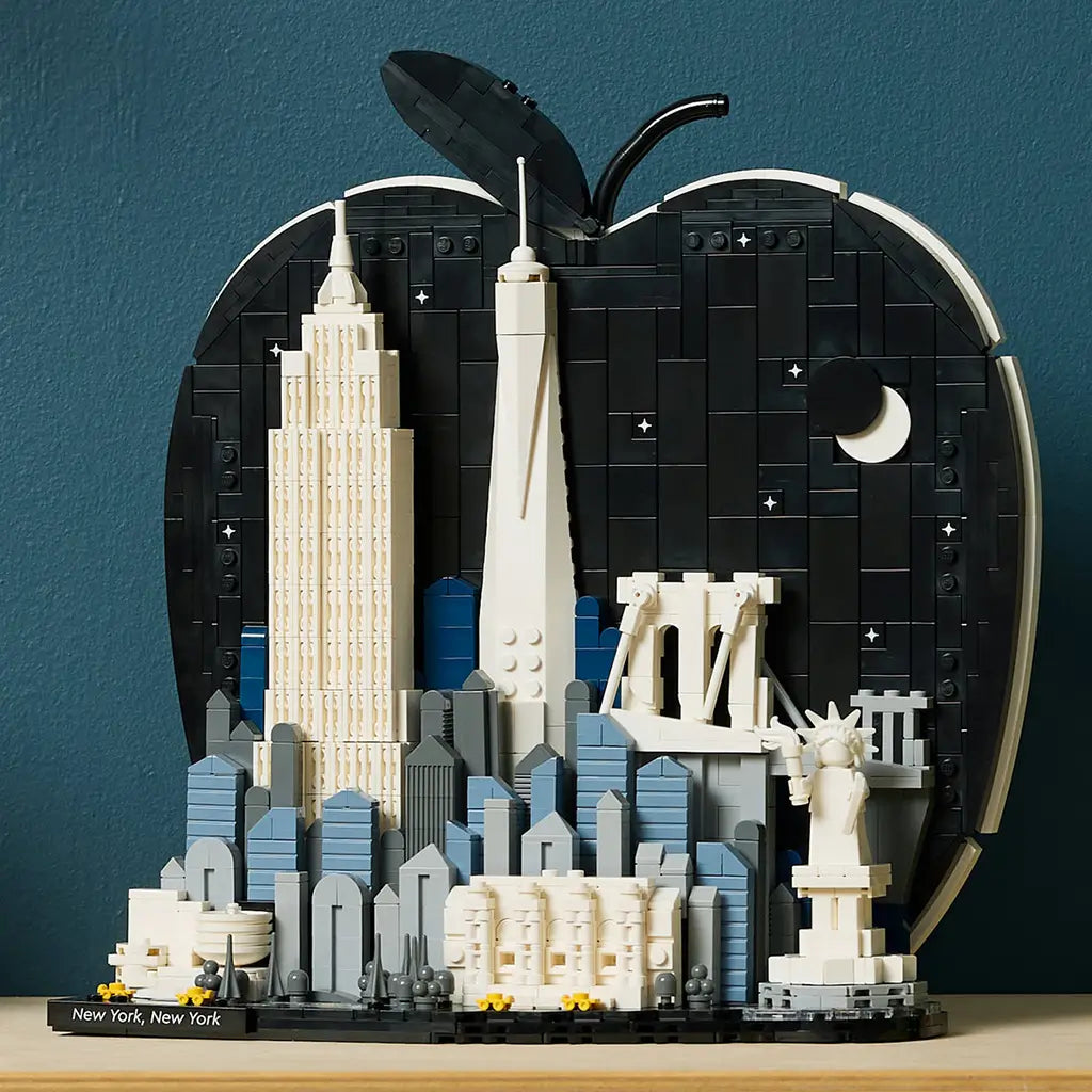 LEGO Architecture New York City model uses black, white, gray and blue plastic bricks to form an apple-shaped skyline with famous landmarks against a teal wall.