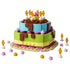 LEGO birthday cake display built from blue, green, pink, tan and brown plastic bricks, forming a two-tier celebration cake with candle decorations, frosting accents and party pieces on a plain studio background.