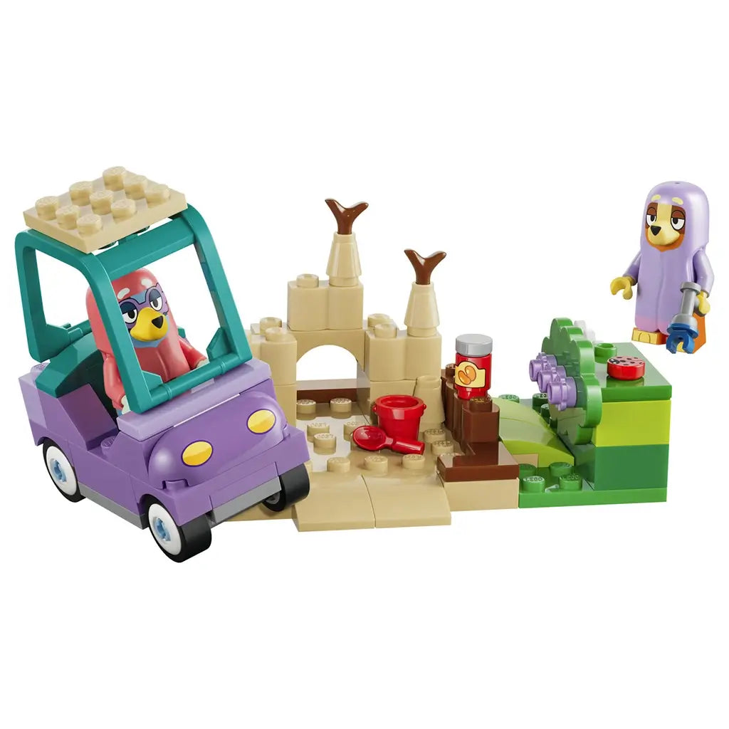 LEGO Bluey Grannies playset in purple, teal, tan, green, pink, and lavender plastic features a toy car, two figures, sandcastle, garden, bucket, shovel, and snack jar on white.