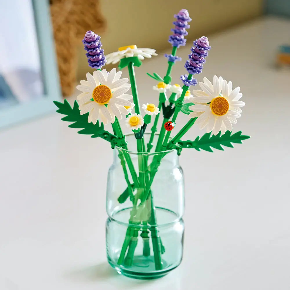 LEGO Botanicals Daisies display showing completed white daisy and lavender bouquet with green stems, elegant plastic brick floral arrangement for home decor, placed in a clear glass jar.