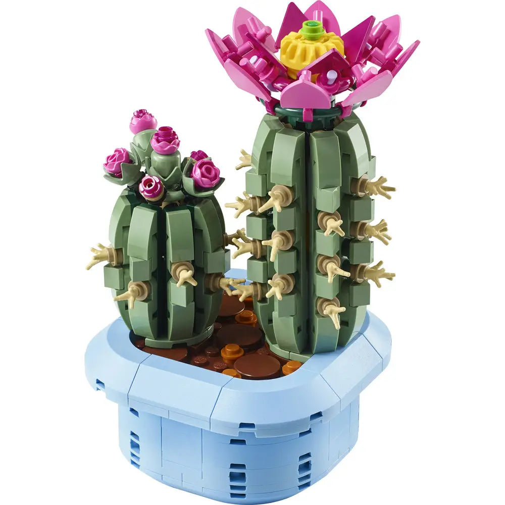 LEGO Botanicals Flowering Cactus set showing green plastic brick cactus with beige spines and a bright pink flower, sculpted cylindrical form for decorative display, arranged in a light blue pot on a clean background.