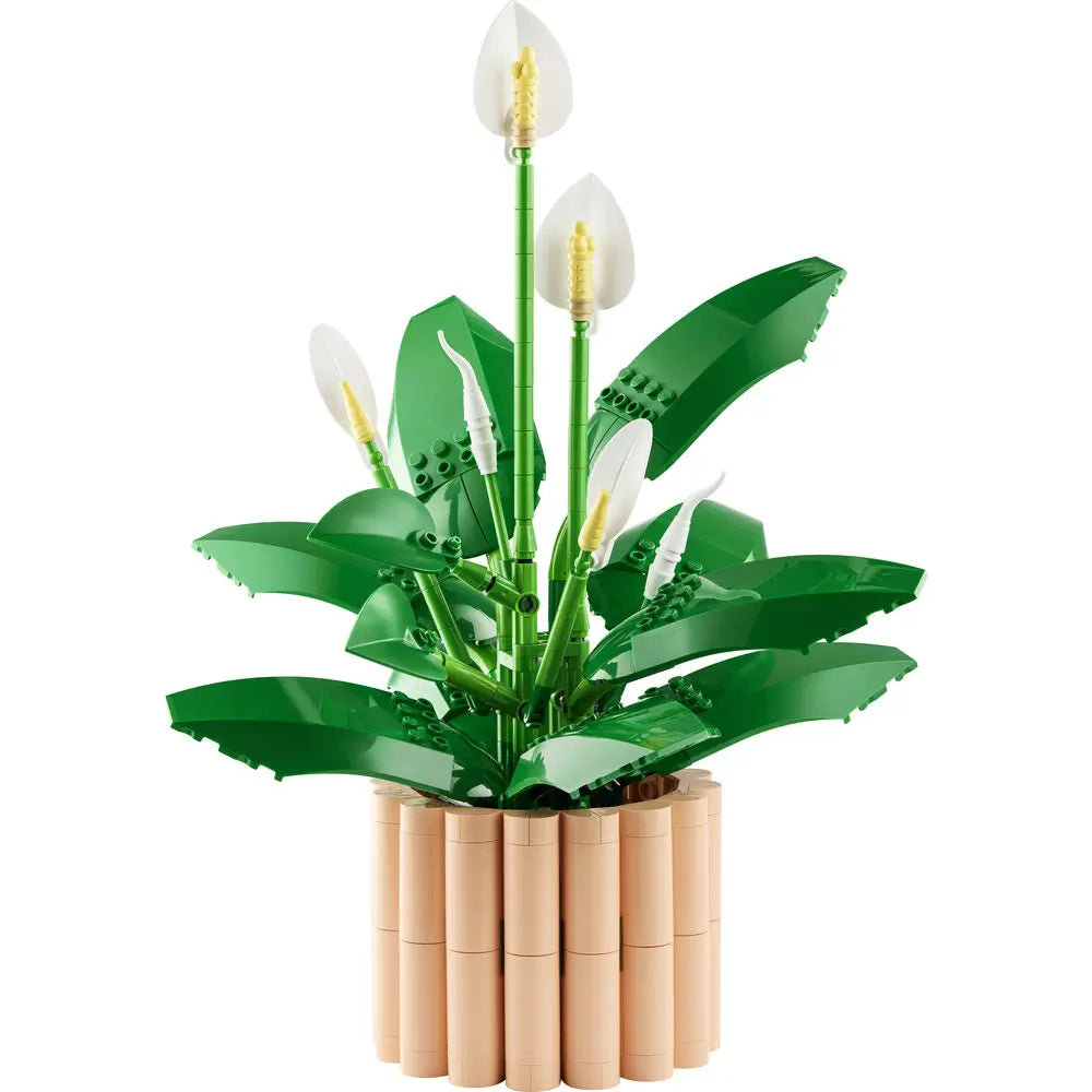 LEGO Botanicals Peace Lily set featuring glossy green plastic leaves with white petal spathes and yellow spadix centers, layered organic shapes for decorative display, arranged in a tan cylindrical brick planter against a white background.