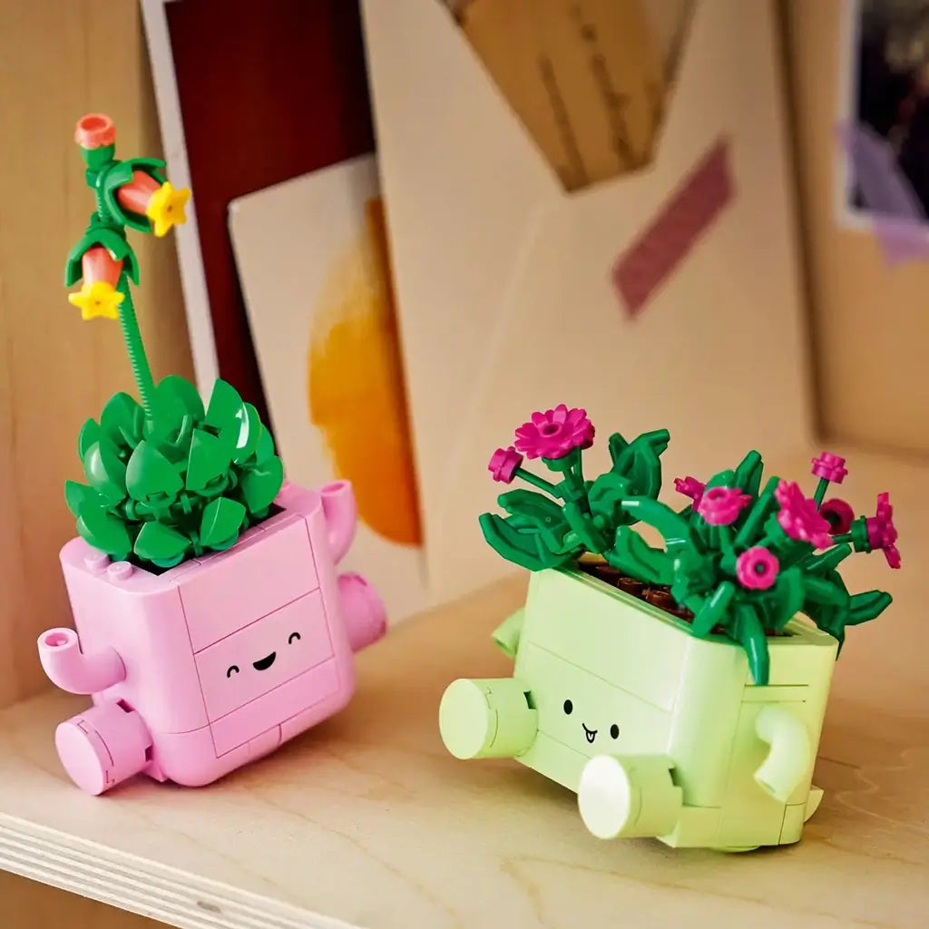 LEGO Botanicals Rocking Plants in pink and light green plastic bricks feature smiling planters with leafy green and magenta flowers, displayed together on a wood shelf.