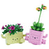 LEGO Botanicals Rocking Plants set in pink and light green bricks shows two smiling planters with green foliage and colorful flowers as a child watches them on a table.