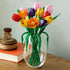 LEGO tulip bouquet displayed in a clear glass vase features multicolored plastic flowers with smooth petals and tall green stems, styled as a decorative centerpiece on a wooden surface indoors.