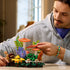LEGO Botanicals Woodland Mushrooms set features orange, yellow, purple, brown, and green plastic fungi and foliage as a builder adjusts the woodland display indoors.