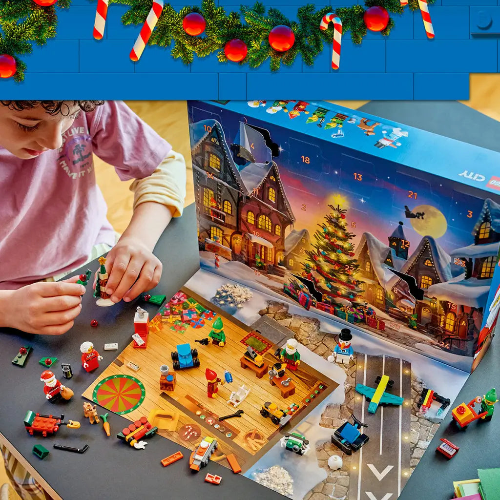 LEGO City Advent Calendar 2026 display shows colorful plastic mini builds and figures on a play mat as a child assembles a Christmas tree beside numbered calendar doors.