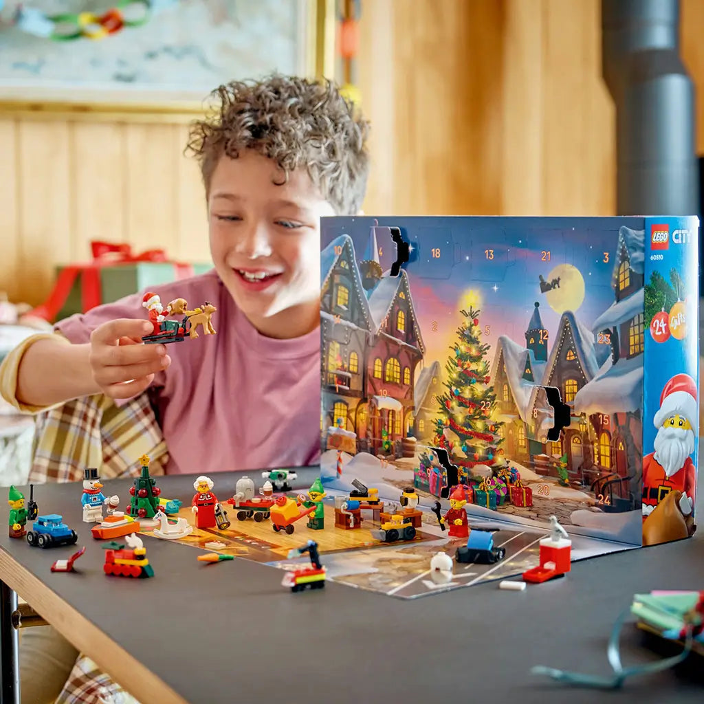 LEGO City Advent Calendar 2026 play scene shows colorful plastic Santa, elves, toys and vehicles as a smiling child holds a sleigh build beside the numbered holiday box.