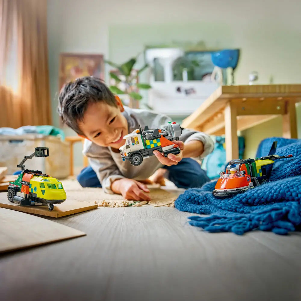 LEGO City lifestyle image of a child playing with a green service truck, yellow rescue airplane, and orange hovercraft, demonstrating imaginative emergency scenarios in a bright indoor home setting.