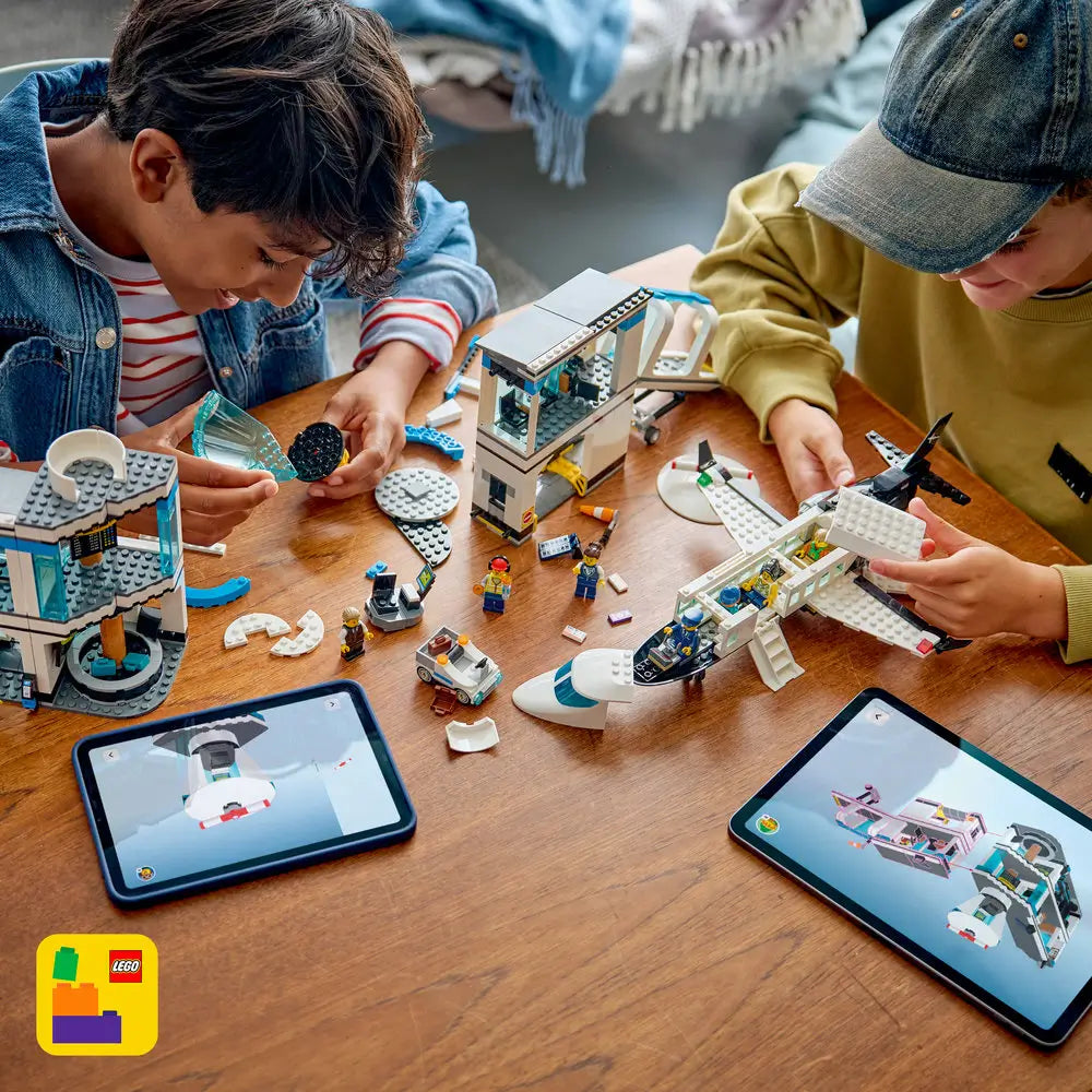 LEGO City airport building set shown in use by children, featuring colorful plastic airplane and terminal pieces spread on a wooden table, encouraging hands-on construction and creative play.