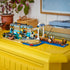 LEGO City Classic Beach Streetcar in turquoise, tan, gray, blue, and brown plastic bricks displays a tram, beach stop, fishing pier, minifigures, dog, seal, and surfboard.