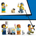 LEGO City beach streetcar minifigures in colorful plastic outfits include tourists with drinks, a pug, vendor with ice cream cart, pigeon, and angler carrying a fish.