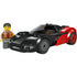 LEGO City EV Supercar shown in black and red plastic bricks with a low, aerodynamic shape, smooth curved panels, enclosed cockpit, and wide wheels, displayed on a clean white background as a compact electric sports car toy.