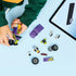 LEGO City Hot Rod partially assembled in purple and lime green plastic bricks, compact low-profile form, with loose parts scattered as a child follows step-by-step digital building instructions on a tablet.