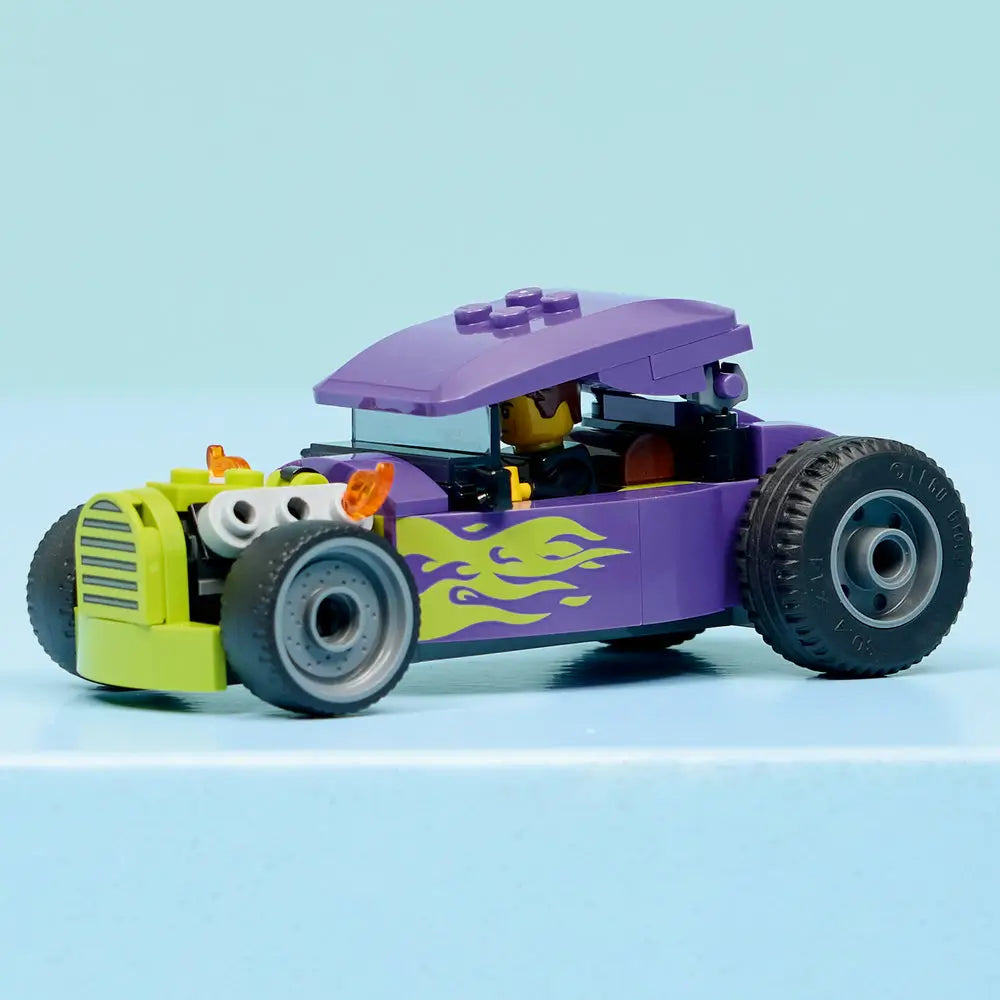 LEGO City Hot Rod fully built display model in purple and lime green plastic bricks, boxy roof, exposed front engine, flame graphics, oversized rear wheels, and minifigure driver on a clean studio background.