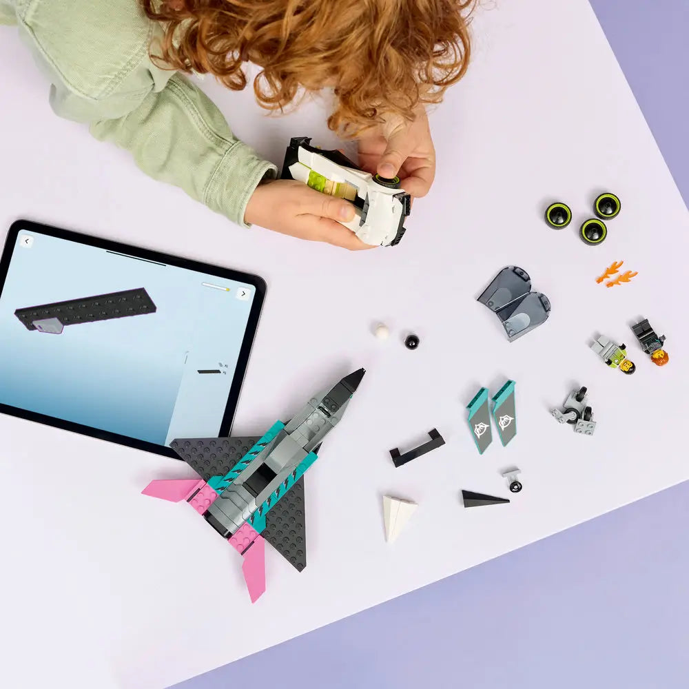 LEGO City Jet vs Car lifestyle build image showing hands assembling the jet and car from gray, teal, pink, and white bricks, with digital instructions visible on a tablet during guided construction.