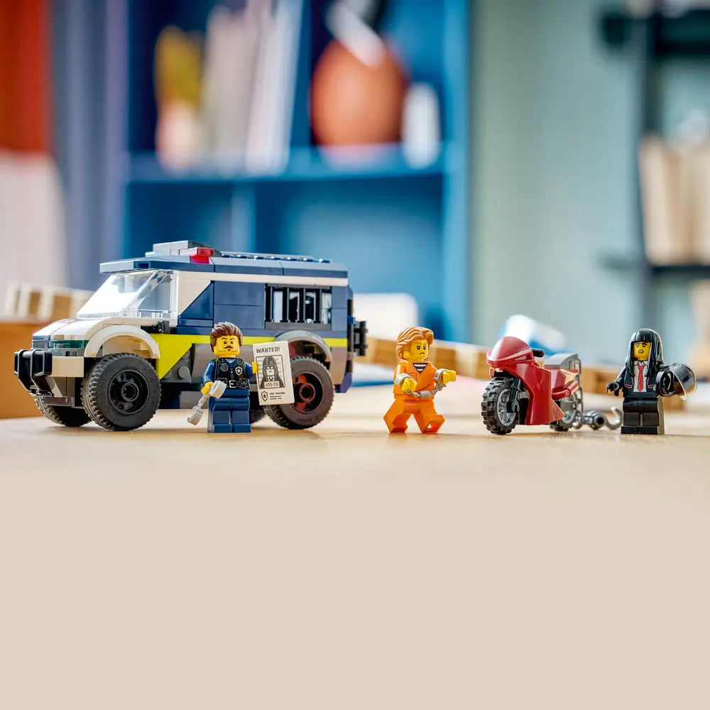 LEGO City police prisoner transport van display with dark blue, white, and yellow plastic bricks, sturdy armored body, barred windows, large wheels, police and criminal minifigures, and a red motorcycle arranged on a tabletop scene.