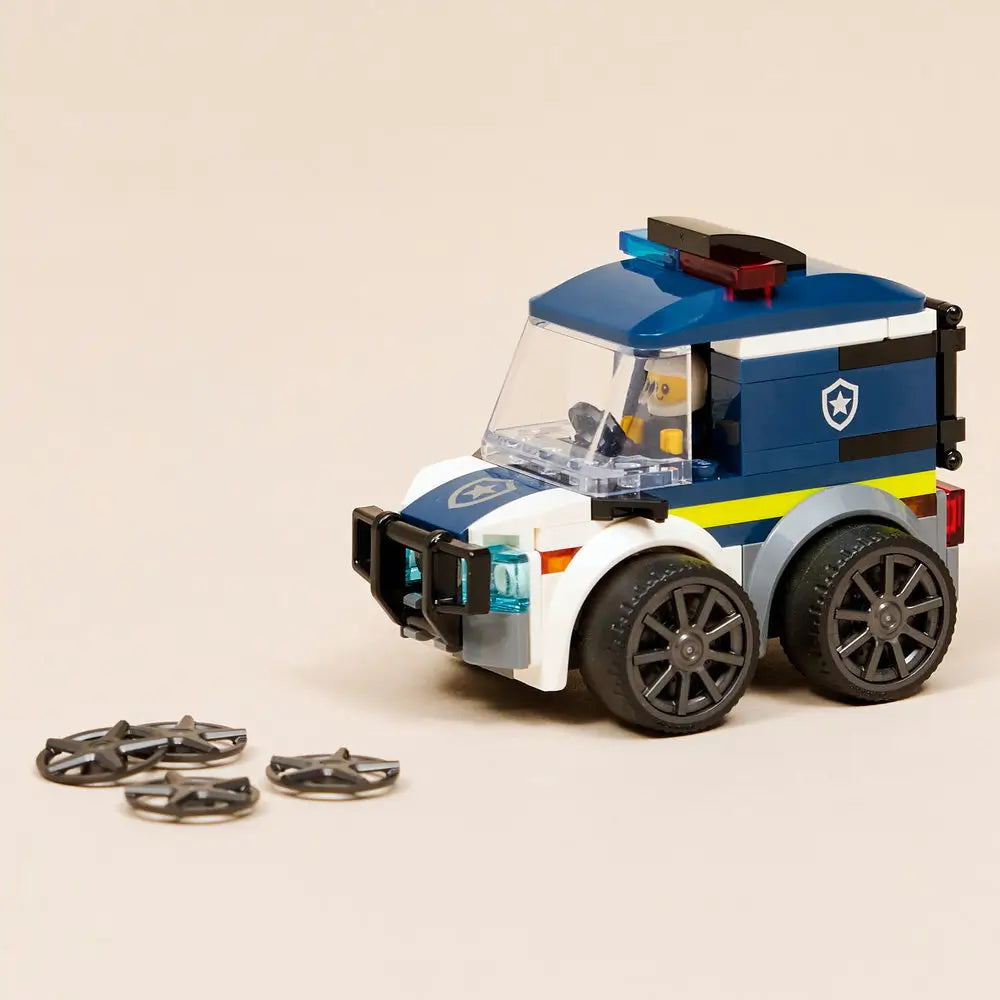 LEGO City Police Truck fully built display model in dark blue and white plastic bricks, sturdy boxy shape, enclosed cab with clear panels, red and blue light bar, large wheels, and police minifigure on a clean studio background.