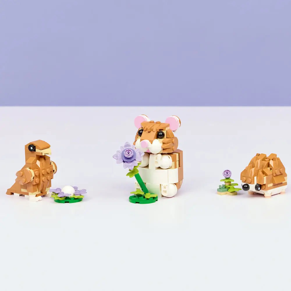 LEGO Creator 3-in-1 hamster models displayed together on a clean surface, showing a hamster, alternate animal build, and small flower accessories made from smooth tan and white plastic bricks.