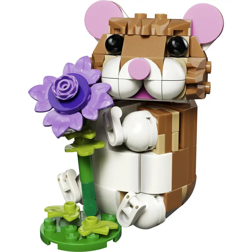 LEGO Creator cute hamster toy built from tan, brown, white, and pink plastic bricks with a smooth glossy texture, rounded upright body shape, large black eyes, small paws, and a purple flower accessory on a clean white background.
