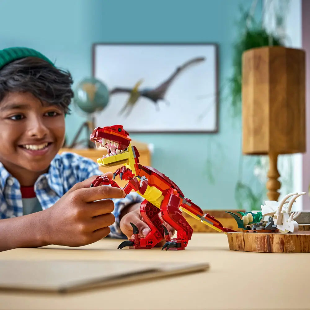 LEGO Creator dinosaur toy in red and yellow plastic bricks as a child plays with the assembled dinosaur figure, emphasizing scale, articulated joints, expressive pose, and imaginative indoor prehistoric play.