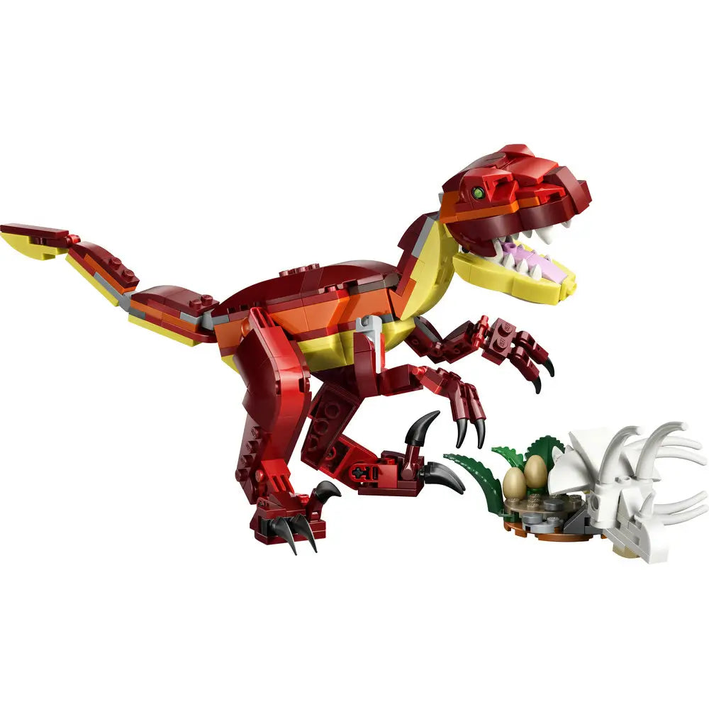 LEGO Creator fierce dinosaur built from red, dark red, and yellow plastic bricks with a smooth glossy texture, angular body shape, open jaw with pointed teeth, clawed legs, and long tail, displayed with a small nest accessory on a white background.
