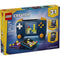 LEGO Creator retro gaming console shown in dark blue plastic bricks with a smooth glossy texture, rounded rectangular shape, colorful screen tiles, control buttons, and handheld controllers, presented on bright yellow and blue retail packaging.