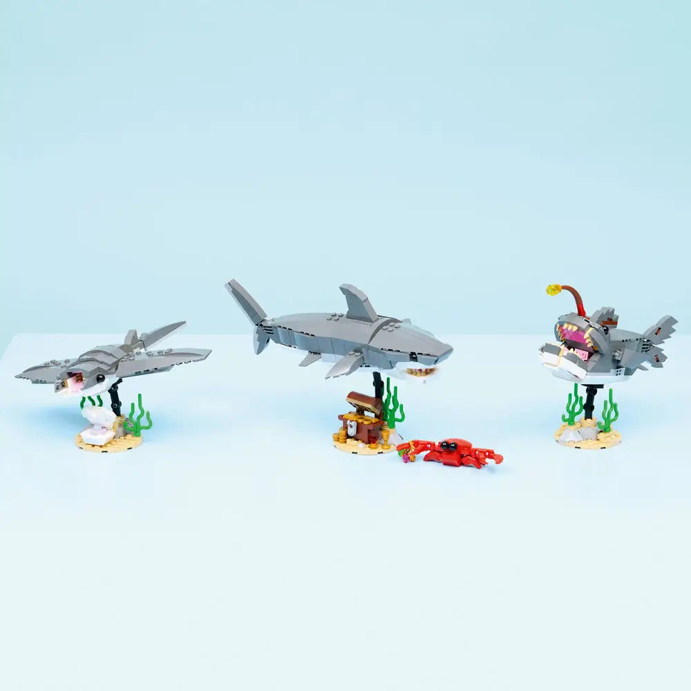 LEGO Creator 3-in-1 sea animal models displayed together on a clean surface, showing a shark, angler fish, and ray built from gray and white plastic bricks with seaweed base details.
