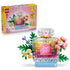 LEGO Creator 3-in-1 set 31383 pairs a pink and yellow box with a clear plastic brick floral perfume bottle featuring green leaves, pink blooms, and a blue base.
