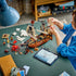 LEGO Creator pirate ship in brown, white and black plastic, as a child fits a white sail to the model beside loose bricks, pirate minifigures, a red sea monster and tablet.