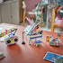 LEGO Creator Music Decor Piano 3-in-1 builds in mint, purple and pink plastic, displaying a grand piano, boombox and record player with music-note decorations on a table.