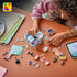 LEGO Creator Music Decor Piano build in mint, purple and pink plastic, as a person assembles the piano model among colorful bricks and digital instructions on a table.