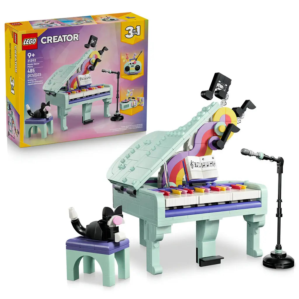 LEGO Creator Music Decor Piano 31392 in mint, purple and pink plastic, with a grand piano, colorful keys, sheet music, black cat, stool and microphone beside the retail box.