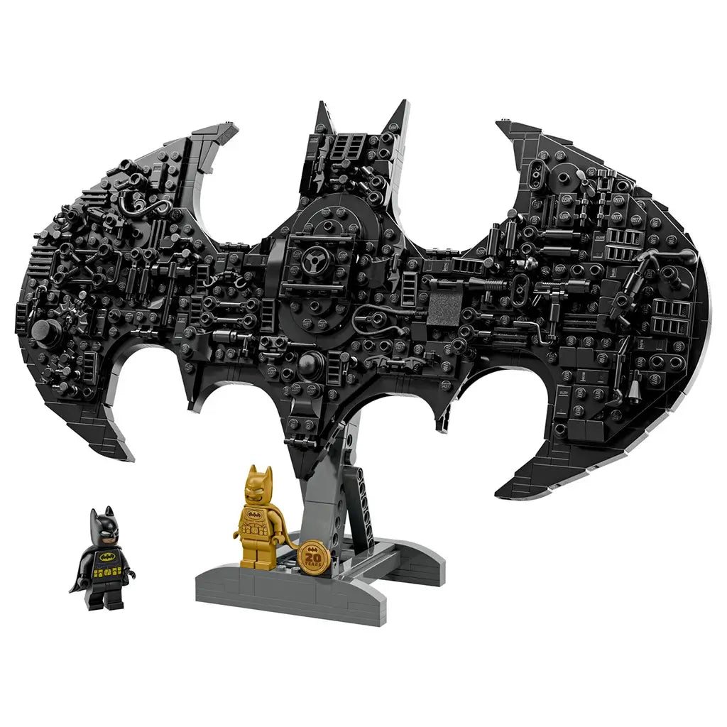 LEGO Batman logo set in black plastic, textured brick-built bat shape with intricate mechanical details, decorative display model on a stand with minifigures against a clean white background.