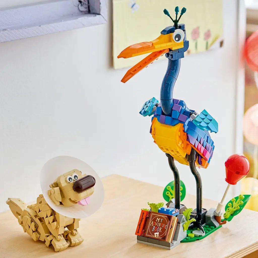 LEGO Disney Pixar Up Kevin and Dug display in multicolor plastic, tall bird with long legs and small dog with cone collar, finished model arranged on a wooden surface with soft home background.