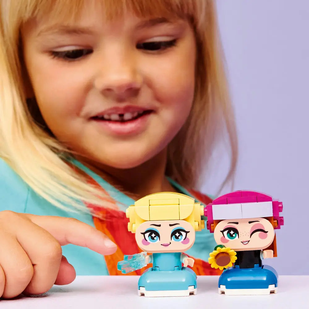 LEGO Disney Frozen Mini Anna and Elsa play experience featuring a child smiling while holding the completed mini figures, highlighting the colorful outfits, expressive faces, and interactive accessories indoors.